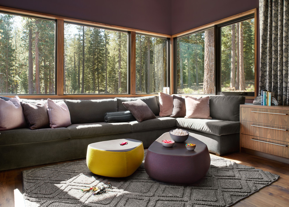 Réalisation d'une grande salle de séjour design fermée avec un mur violet, un sol marron et un sol en bois brun.