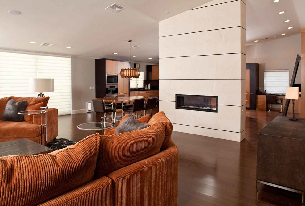 Inspiration for an expansive contemporary open plan games room in Las Vegas with beige walls, medium hardwood flooring, a two-sided fireplace, a tiled fireplace surround and brown floors.
