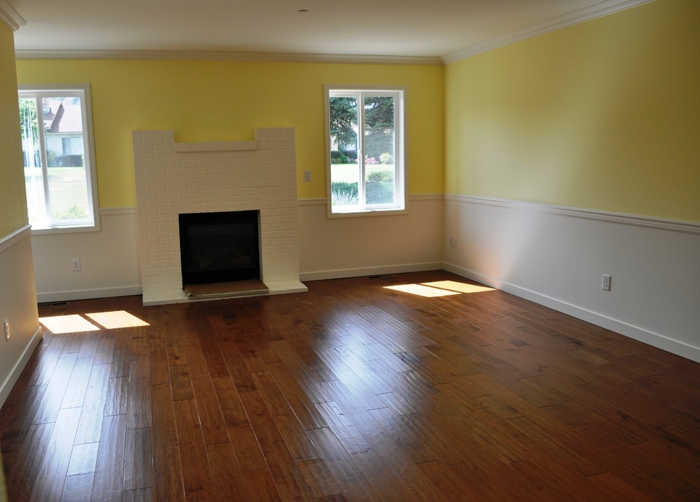 Foto de sala de estar cerrada tradicional renovada pequeña con paredes amarillas, suelo de madera en tonos medios, todas las chimeneas, marco de chimenea de ladrillo y pared multimedia