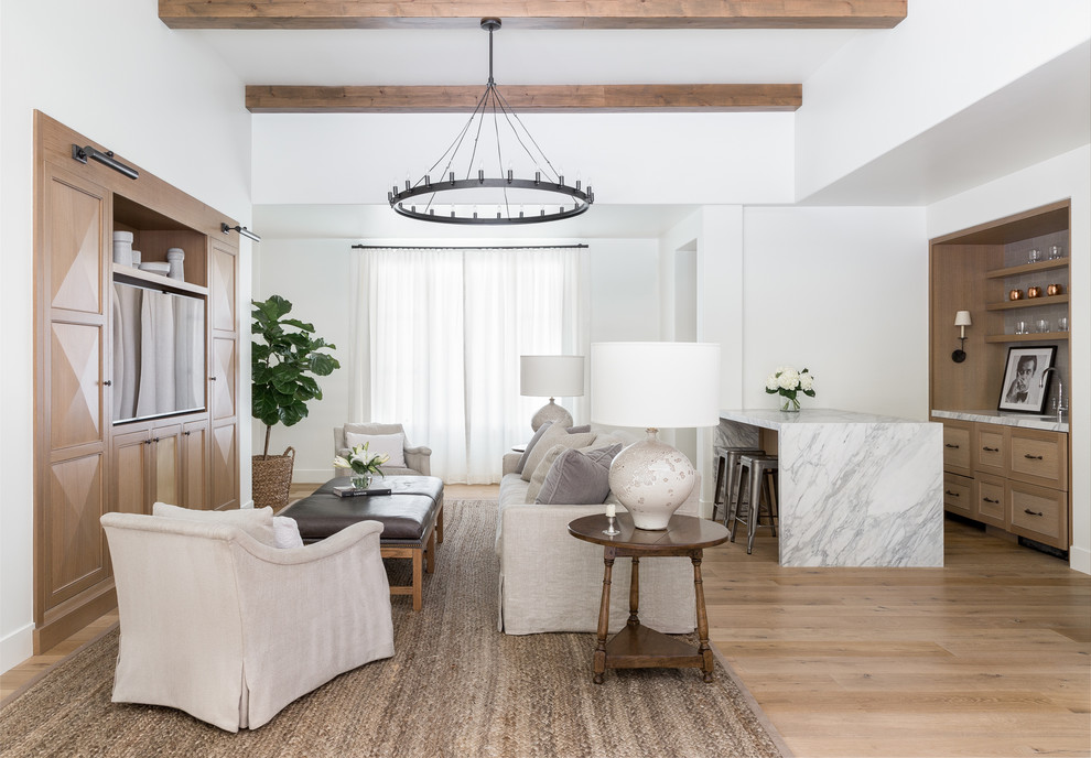 Diseño de sala de estar con barra de bar abierta tradicional renovada sin chimenea con paredes blancas, suelo de madera clara y pared multimedia