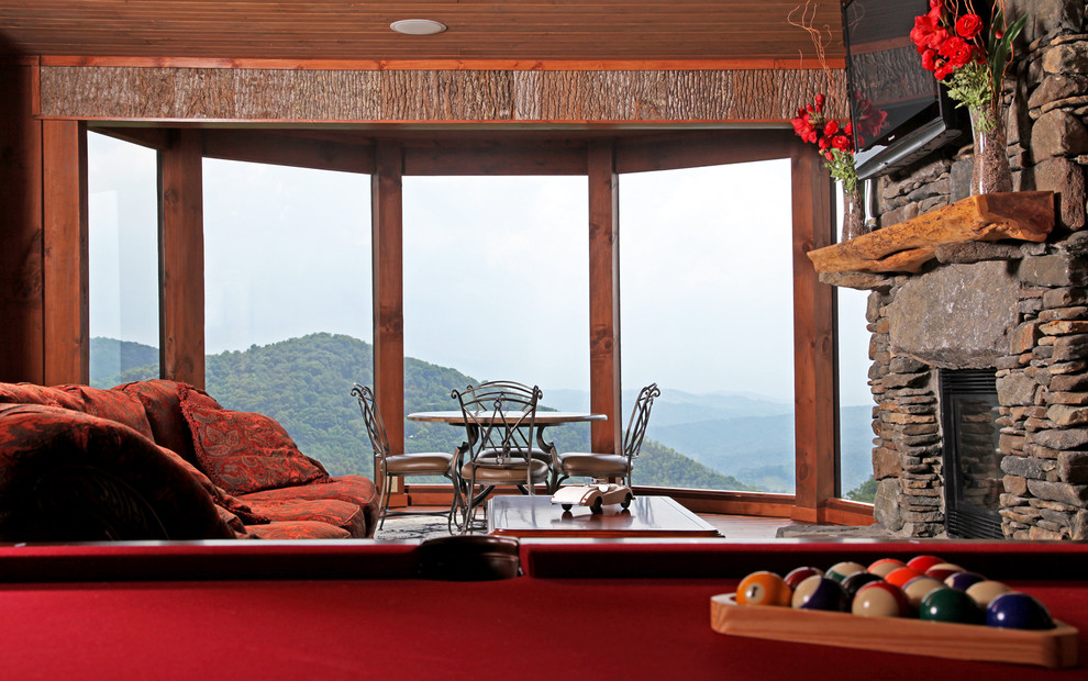 Example of a large mountain style enclosed carpeted game room design in Charlotte with brown walls, a standard fireplace, a stone fireplace and a wall-mounted tv