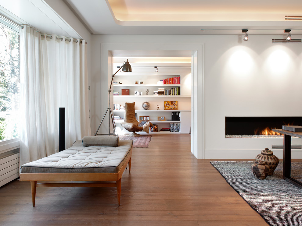 Imagen de sala de estar abierta nórdica de tamaño medio sin televisor con paredes blancas, suelo de madera en tonos medios y chimenea lineal