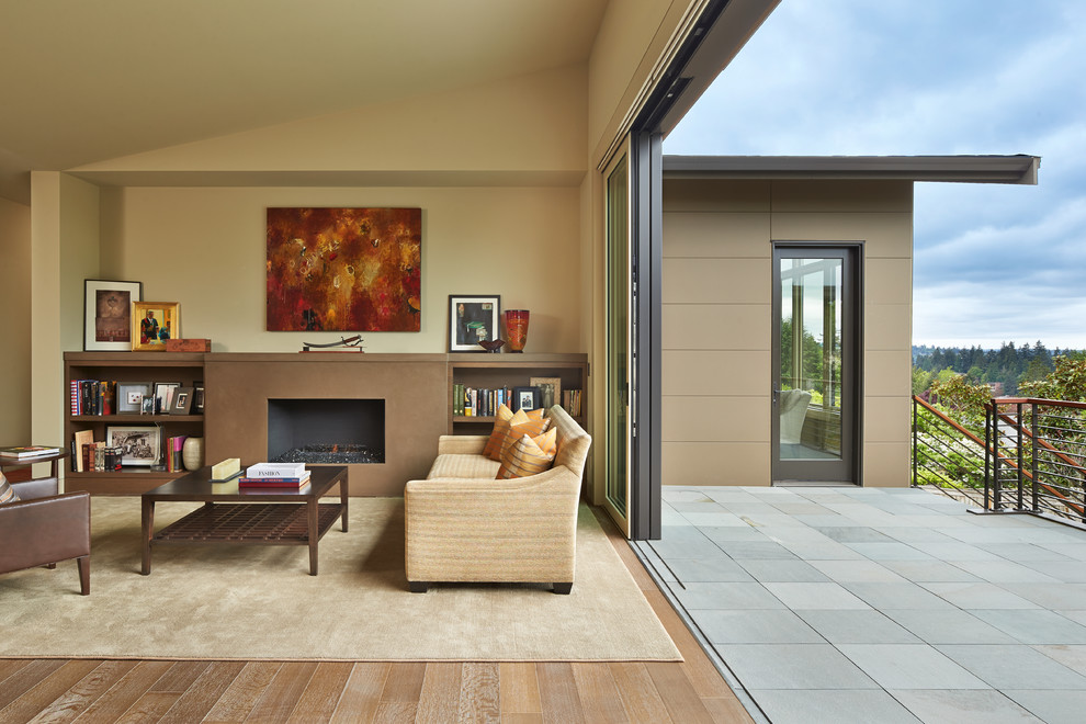 Foto de sala de estar abierta contemporánea grande con paredes beige, suelo de madera clara, todas las chimeneas y marco de chimenea de hormigón