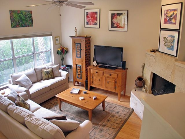 Foto de sala de estar tradicional pequeña con paredes beige, suelo de madera clara, televisor independiente, chimenea de esquina y marco de chimenea de baldosas y/o azulejos