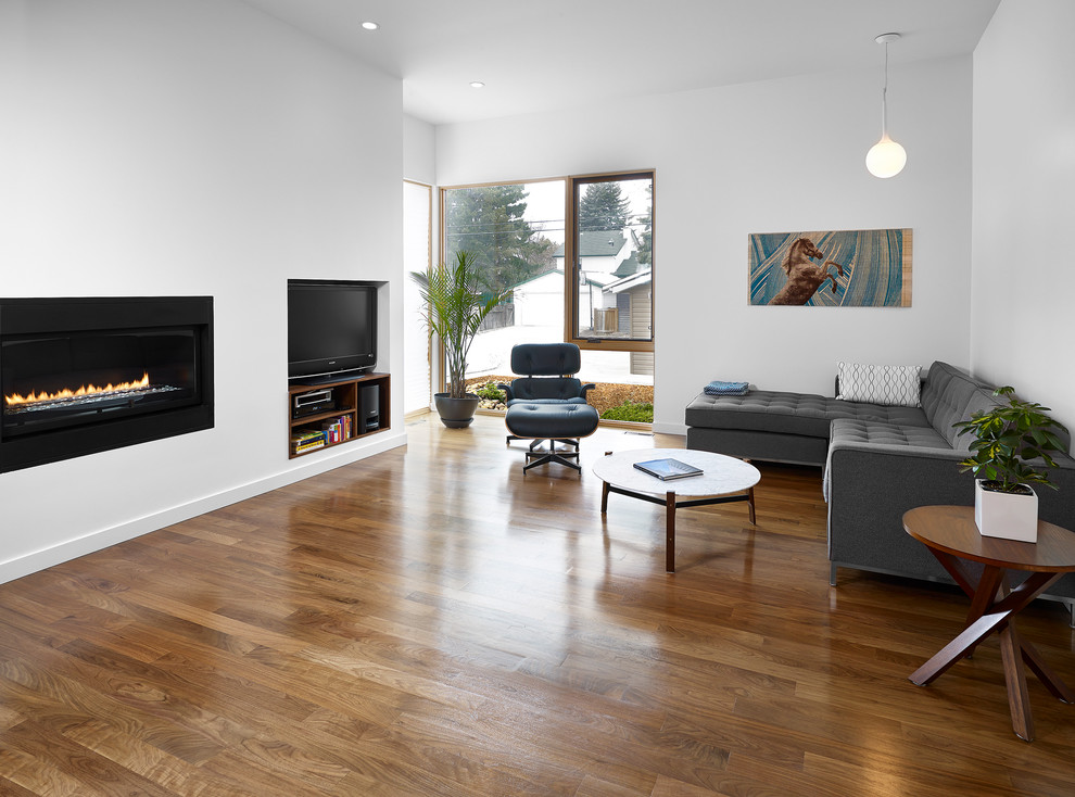 Imagen de sala de estar cerrada contemporánea de tamaño medio con paredes blancas, suelo de madera en tonos medios, chimenea lineal, marco de chimenea de yeso, pared multimedia y suelo marrón