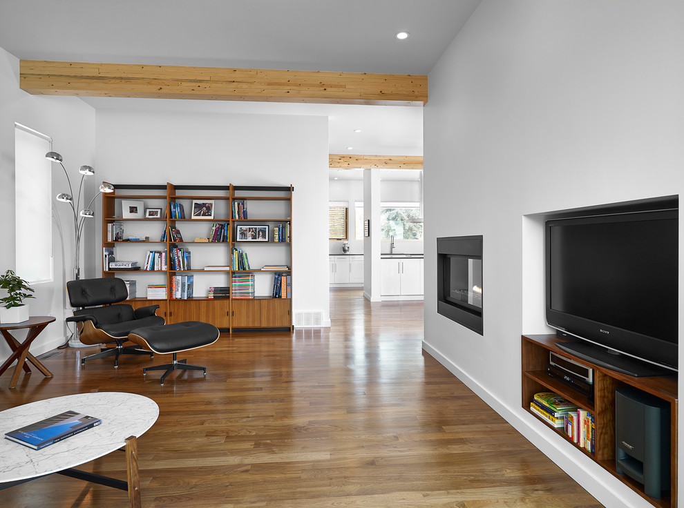 Mittelgroßes, Abgetrenntes Modernes Wohnzimmer mit weißer Wandfarbe, braunem Holzboden, Gaskamin, verputzter Kaminumrandung, Multimediawand und braunem Boden in Edmonton