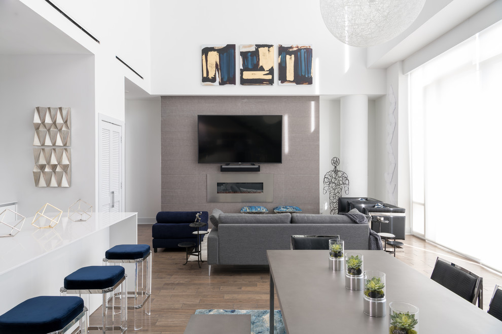 Offenes Modernes Wohnzimmer mit grauer Wandfarbe, braunem Holzboden, Gaskamin, Kaminumrandung aus Metall und TV-Wand in Dallas