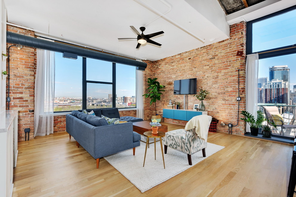 Modelo de sala de estar abierta urbana con paredes rojas, suelo de madera clara, televisor colgado en la pared y suelo beige