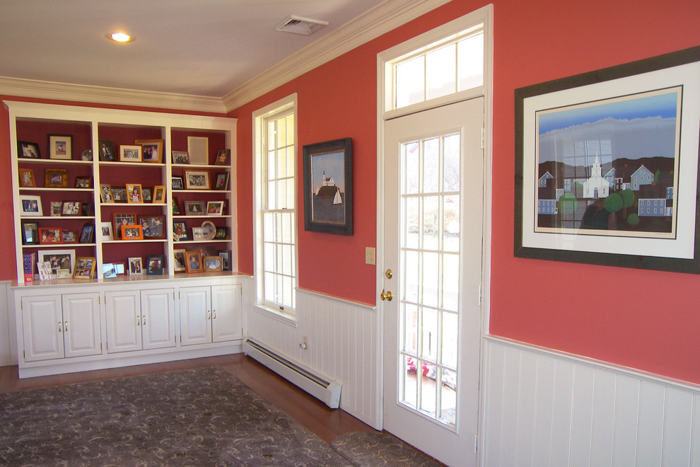 Idée de décoration pour une grande salle de séjour tradition ouverte avec une bibliothèque ou un coin lecture, un mur rouge, un sol en bois brun, une cheminée standard, un manteau de cheminée en pierre et un téléviseur fixé au mur.