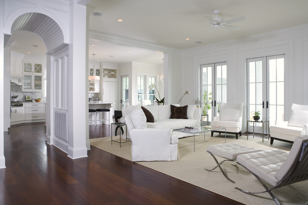 Elegant open concept dark wood floor and brown floor family room photo in Charleston with white walls