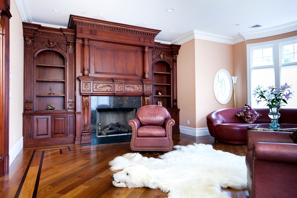 Imagen de sala de estar cerrada tradicional de tamaño medio sin televisor con parades naranjas, suelo de madera en tonos medios, todas las chimeneas y marco de chimenea de madera