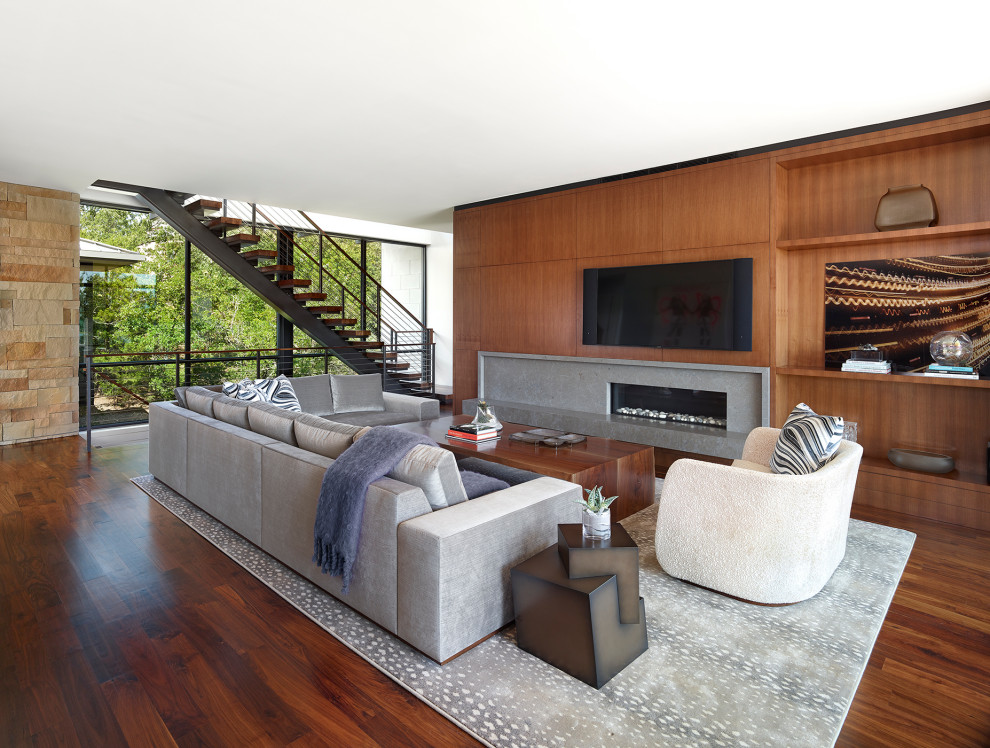 На фото: огромная открытая гостиная комната в современном стиле с паркетным полом среднего тона, телевизором на стене, коричневым полом, коричневыми стенами и горизонтальным камином