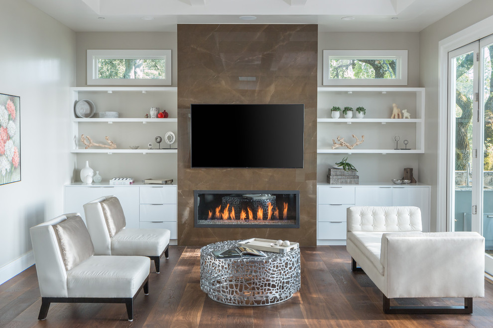 Modelo de sala de estar cerrada contemporánea con paredes beige, suelo de madera oscura, chimenea lineal, marco de chimenea de baldosas y/o azulejos y televisor colgado en la pared