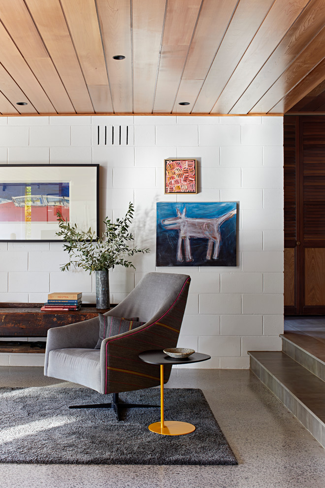 This is an example of a medium sized midcentury open plan games room in Melbourne with white walls, concrete flooring and grey floors.