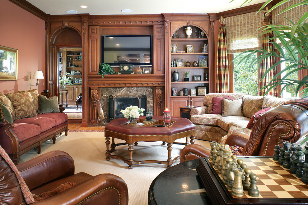 Foto de sala de estar con biblioteca abierta clásica grande con suelo de madera en tonos medios, todas las chimeneas, marco de chimenea de madera, pared multimedia y parades naranjas