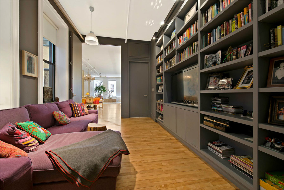 Immagine di un piccolo soggiorno industriale chiuso con libreria, pareti nere, parquet chiaro, nessun camino e TV a parete
