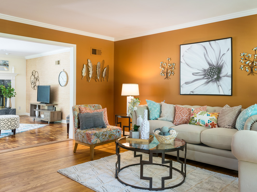 На фото: изолированная гостиная комната среднего размера в стиле неоклассика (современная классика) с оранжевыми стенами, темным паркетным полом и серым полом без камина, телевизора с