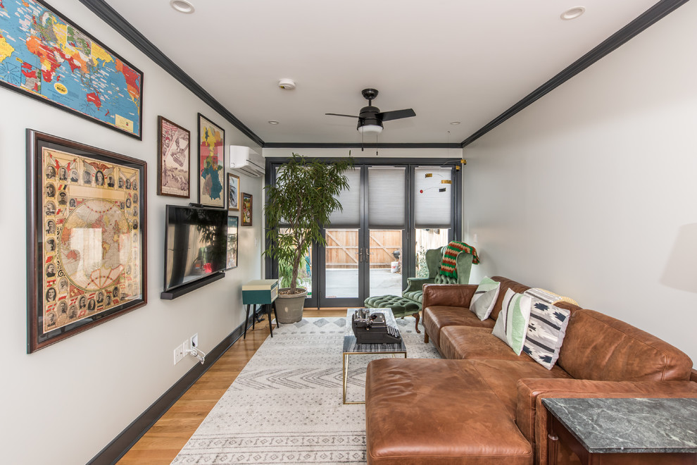 Immagine di un piccolo soggiorno chic aperto con pareti bianche, pavimento in legno massello medio, TV a parete e pavimento marrone