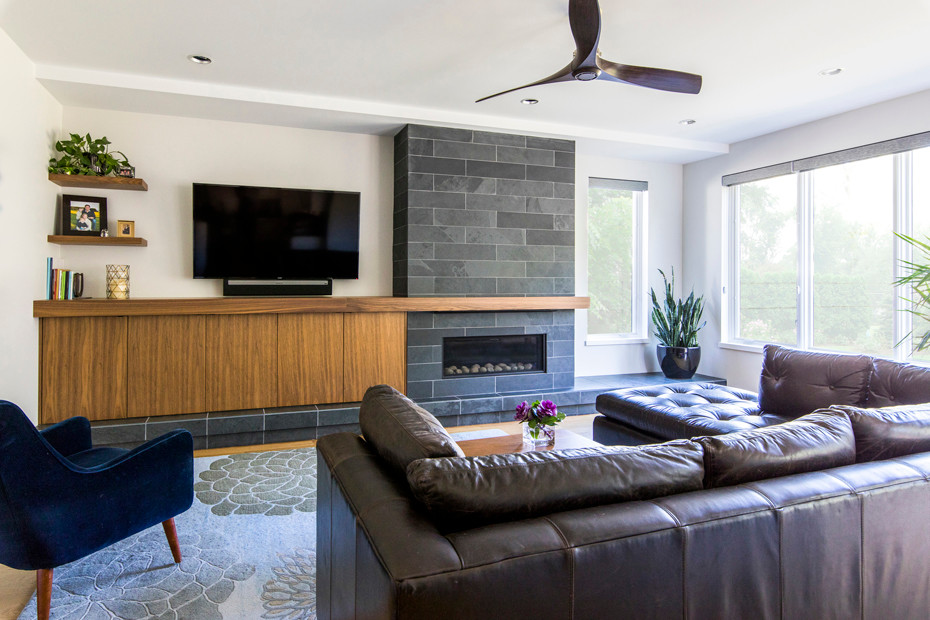 Foto de sala de estar abierta actual de tamaño medio con paredes grises, suelo de madera clara, todas las chimeneas, marco de chimenea de piedra y televisor colgado en la pared