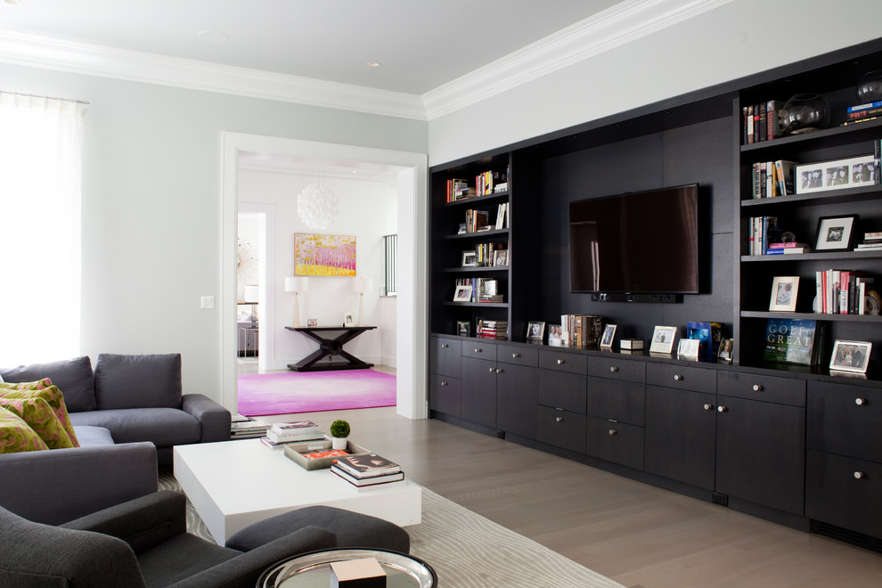 На фото: гостиная комната в современном стиле с серыми стенами, паркетным полом среднего тона и мультимедийным центром без камина