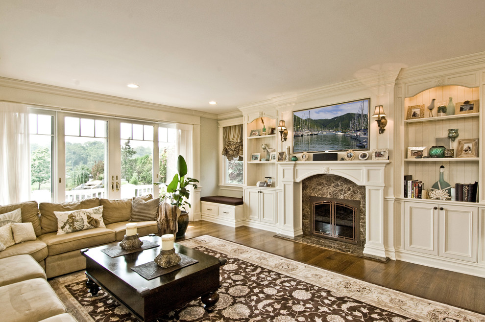 Klassisches Wohnzimmer mit beiger Wandfarbe, dunklem Holzboden, Kamin, Kaminumrandung aus Stein und TV-Wand in New York
