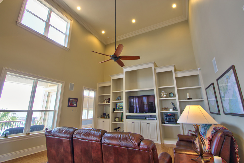 Imagen de sala de estar abierta tradicional de tamaño medio sin chimenea con paredes beige, suelo de madera en tonos medios y pared multimedia