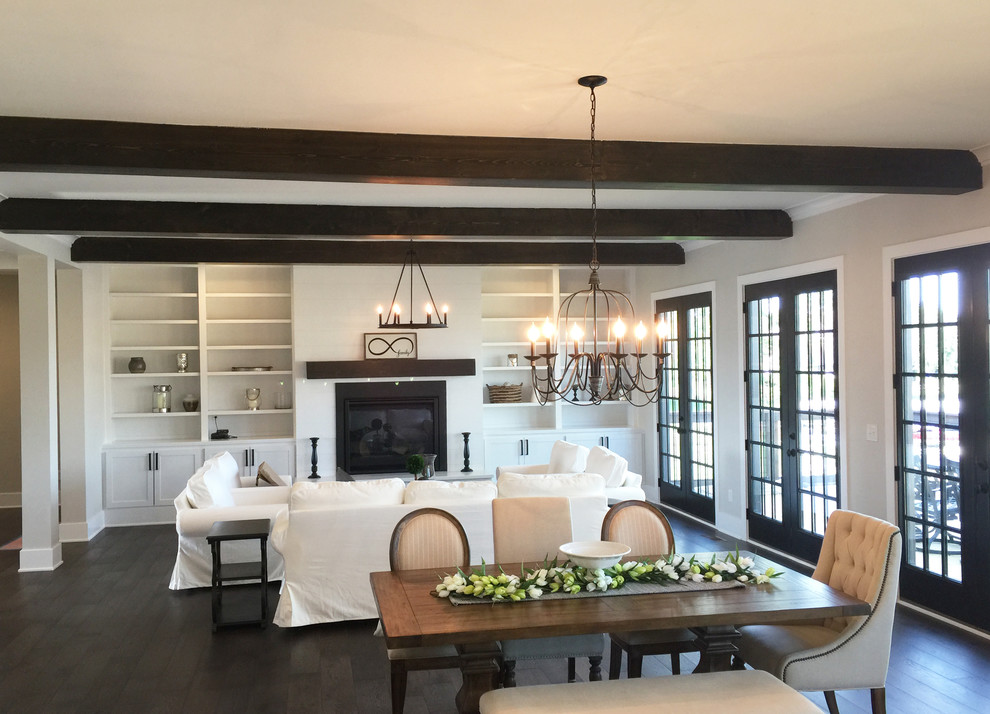 This is an example of a large country open plan games room in Indianapolis with white walls, dark hardwood flooring, a standard fireplace, a wooden fireplace surround and brown floors.