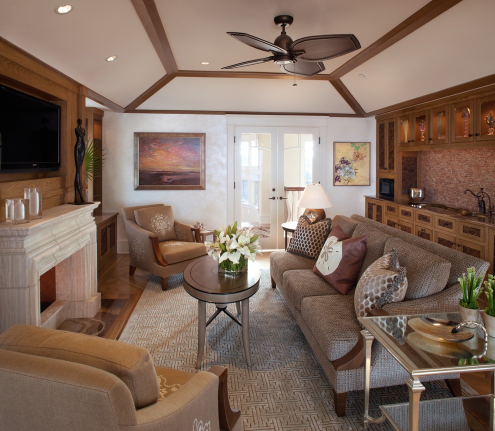 Medium sized world-inspired games room in Philadelphia with medium hardwood flooring, a standard fireplace, a stone fireplace surround, a wall mounted tv, a home bar and beige walls.