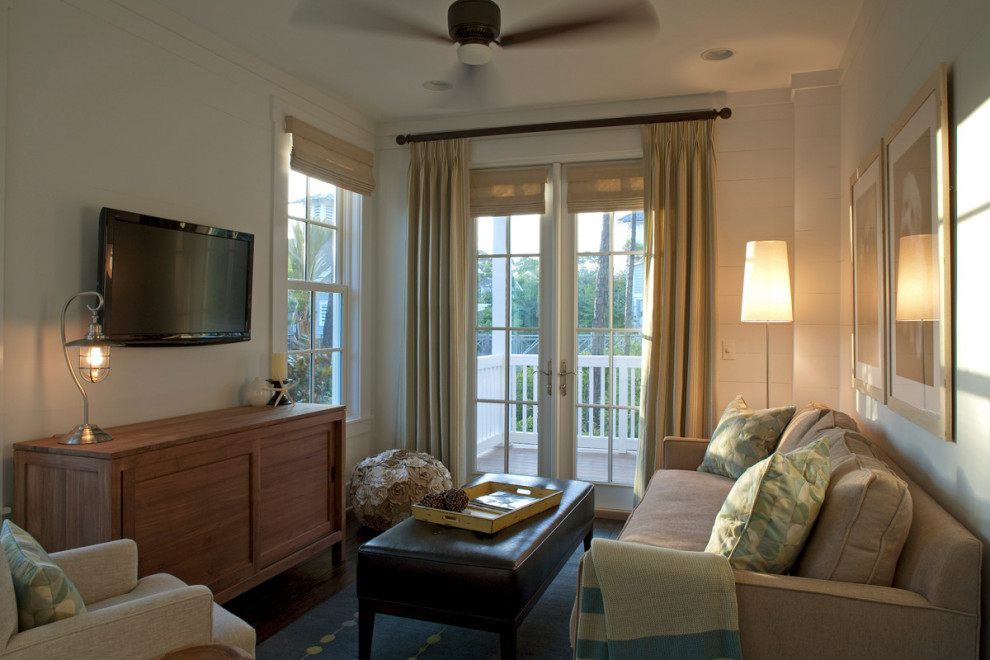 На фото: изолированная гостиная комната среднего размера в морском стиле с белыми стенами, темным паркетным полом и телевизором на стене без камина