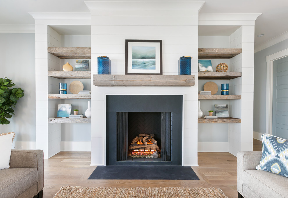 Mittelgroßes, Offenes Maritimes Wohnzimmer mit braunem Holzboden, Kamin, Kaminumrandung aus Stein und braunem Boden in Charleston