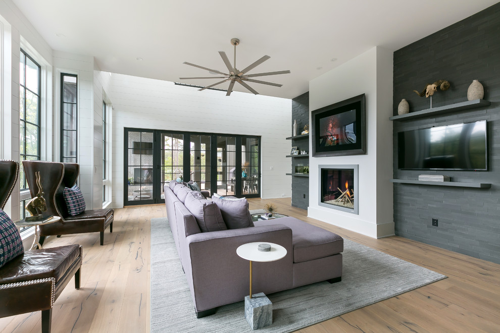 Modelo de sala de estar actual con paredes blancas, suelo de madera en tonos medios, todas las chimeneas y marco de chimenea de metal