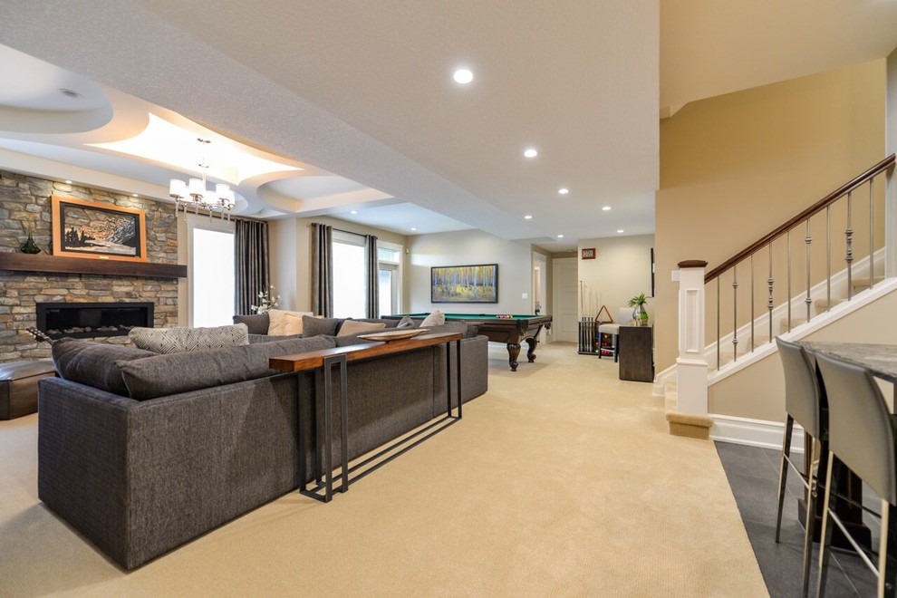 This is an example of a large traditional open plan games room in Calgary with a game room, white walls, carpet, a ribbon fireplace and a stone fireplace surround.