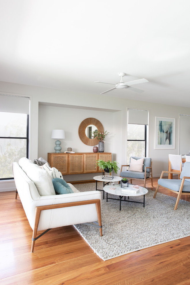 Example of a danish medium tone wood floor and brown floor family room design in Brisbane with gray walls