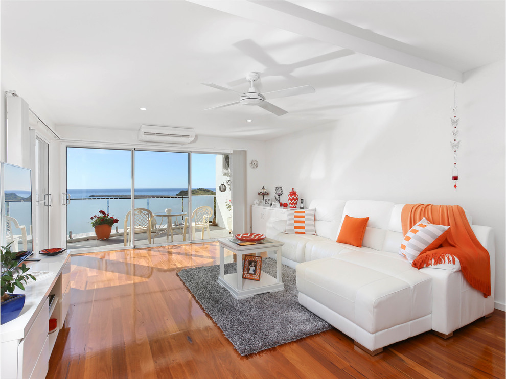 Esempio di un soggiorno costiero aperto con pareti bianche, pavimento in legno massello medio e pavimento arancione
