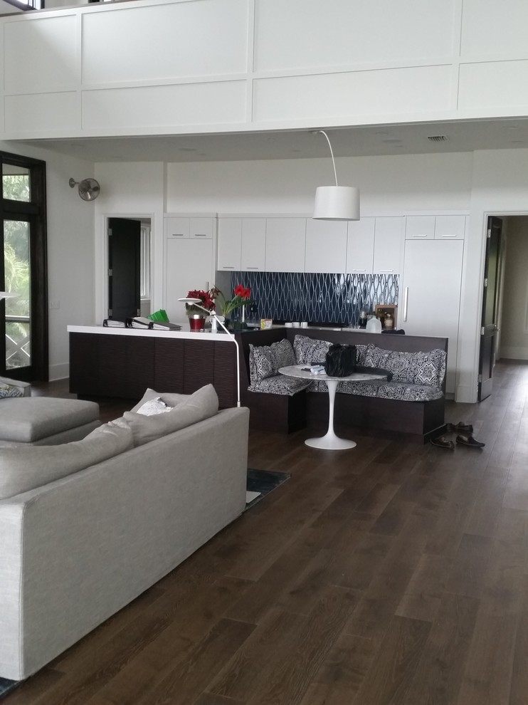 Imagen de sala de estar abierta costera de tamaño medio con paredes blancas, suelo de madera clara, chimeneas suspendidas, marco de chimenea de madera y suelo beige
