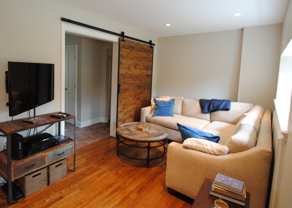 Diseño de sala de estar cerrada rural de tamaño medio sin chimenea con suelo de madera en tonos medios, televisor colgado en la pared y paredes beige