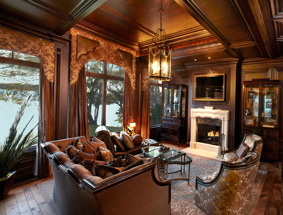 Imagen de sala de estar clásica con paredes marrones, suelo de madera oscura, todas las chimeneas, marco de chimenea de piedra y televisor colgado en la pared