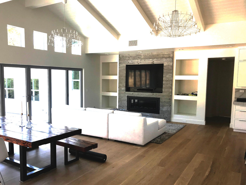 Inspiration for a large craftsman open concept light wood floor and brown floor family room remodel in San Francisco with white walls, a standard fireplace, a concrete fireplace and a media wall