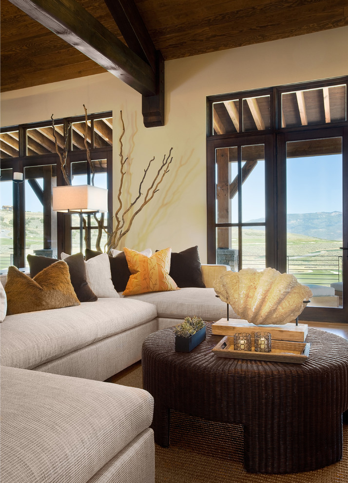 Cette image montre une grande salle de séjour design fermée avec un mur beige et un sol en bois brun.