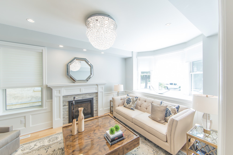 Mittelgroßes, Fernseherloses, Abgetrenntes Modernes Wohnzimmer mit beiger Wandfarbe, hellem Holzboden, Kamin und verputzter Kaminumrandung in Toronto