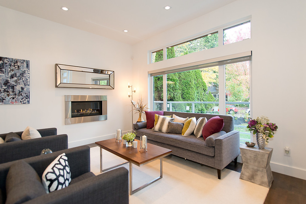 This is an example of a medium sized modern open plan games room in Vancouver with white walls, dark hardwood flooring, a ribbon fireplace, a metal fireplace surround, no tv and brown floors.