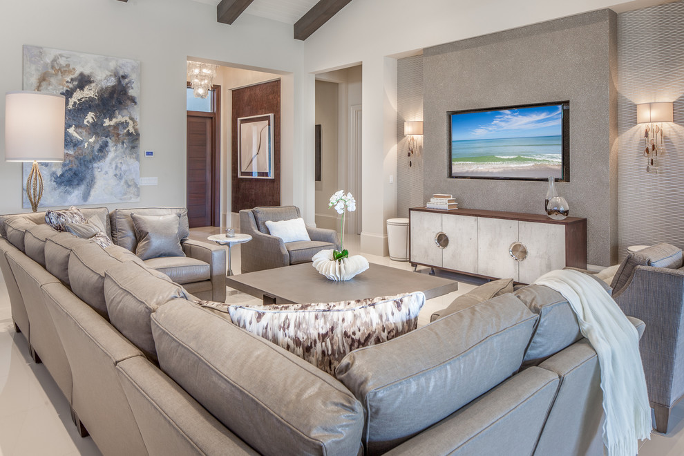 Diseño de sala de estar abierta costera con paredes beige, televisor colgado en la pared y suelo beige