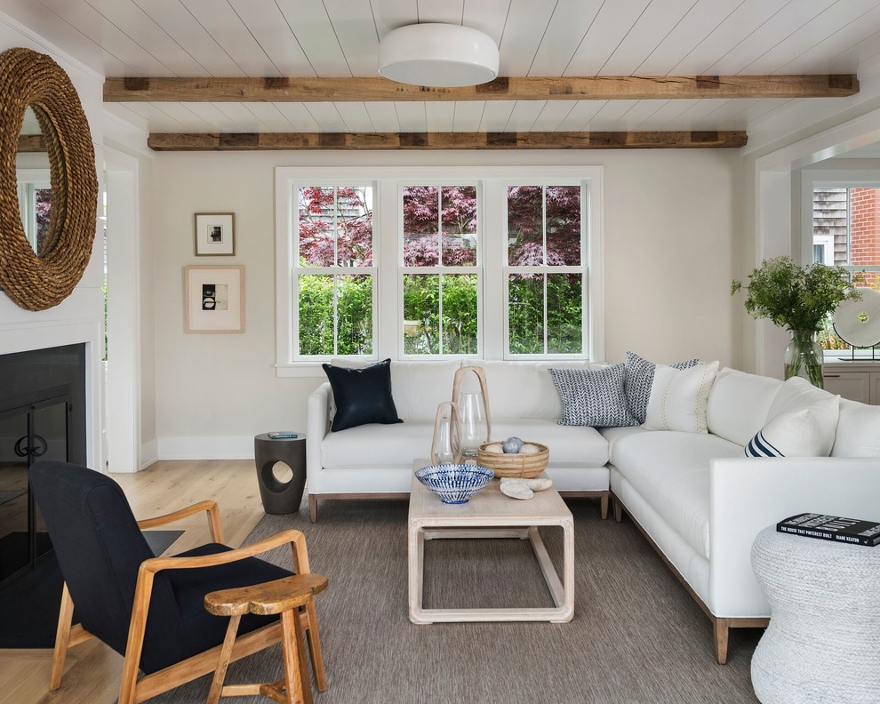 Imagen de sala de estar abierta costera grande sin televisor con paredes beige, suelo de madera clara, todas las chimeneas y suelo beige