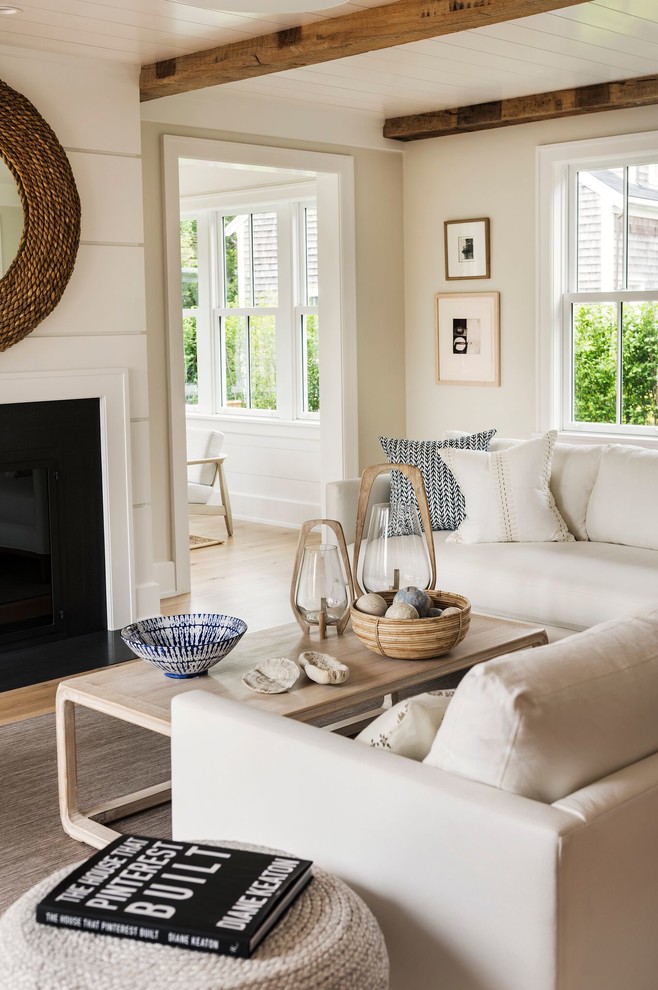 Diseño de sala de estar abierta costera grande sin televisor con paredes beige, suelo de madera clara, todas las chimeneas y suelo beige