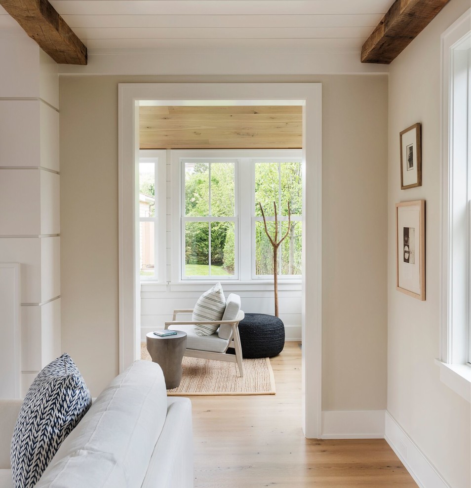Imagen de sala de estar abierta marinera grande sin televisor con paredes beige, suelo de madera clara, todas las chimeneas y suelo beige