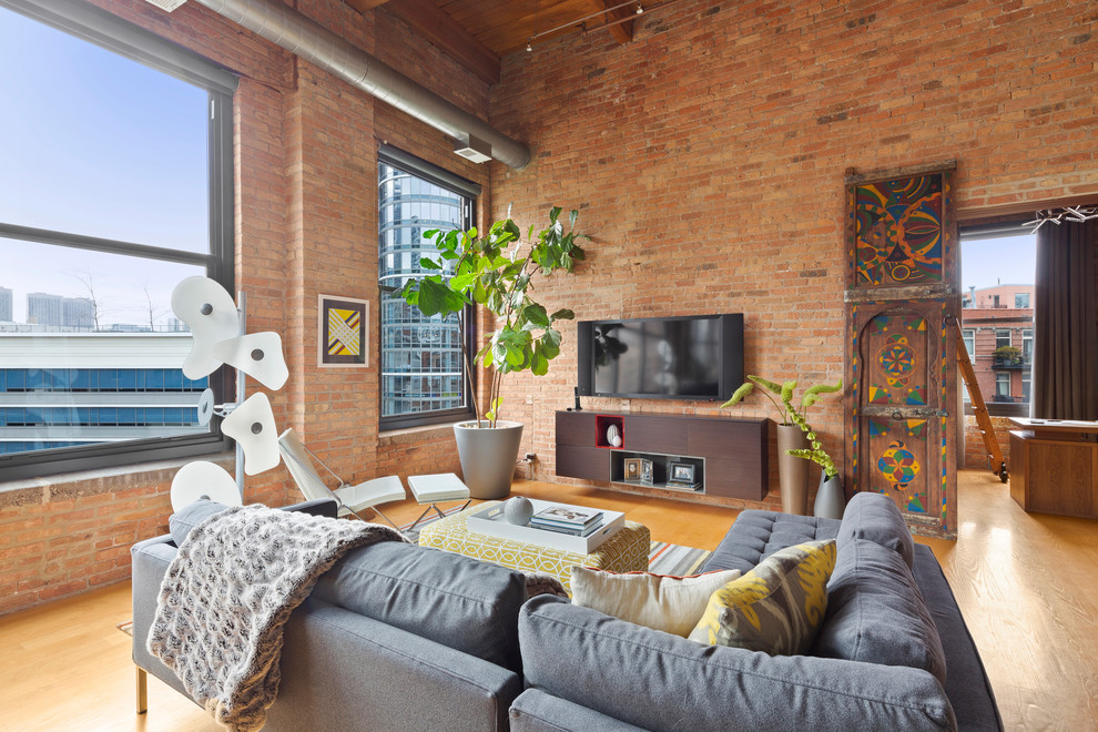 Offenes Industrial Wohnzimmer ohne Kamin mit roter Wandfarbe, hellem Holzboden und TV-Wand in Chicago