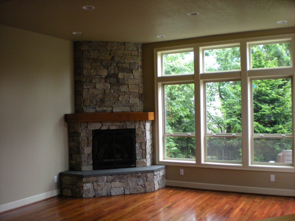 Mittelgroßes, Abgetrenntes Klassisches Wohnzimmer mit beiger Wandfarbe, braunem Holzboden, Eckkamin, Kaminumrandung aus Stein und braunem Boden in Portland