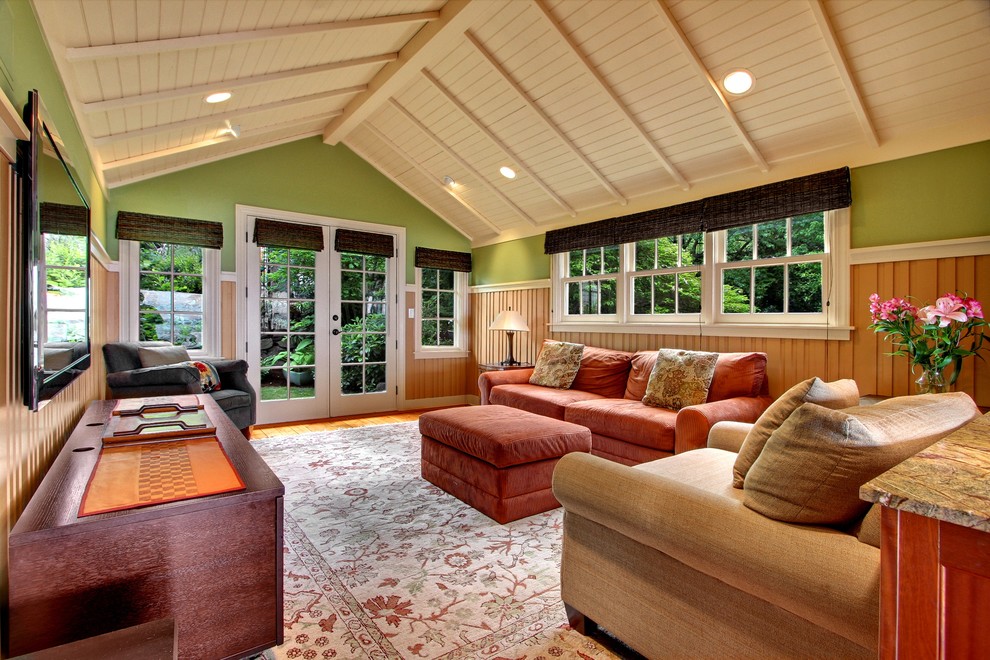 На фото: гостиная комната в стиле кантри с зелеными стенами, паркетным полом среднего тона, телевизором на стене и ковром на полу без камина с