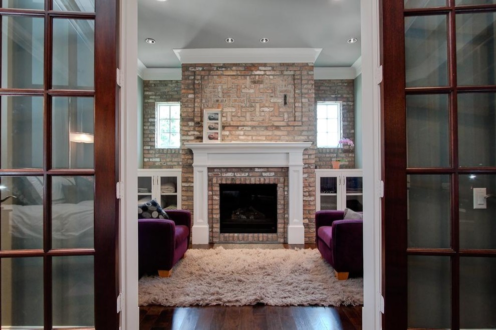 Пример оригинального дизайна: гостиная комната в классическом стиле с фасадом камина из кирпича, скрытым телевизором и ковром на полу