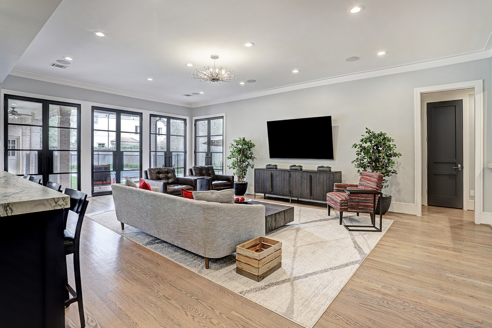 Diseño de sala de estar abierta clásica renovada grande con paredes azules, suelo de madera clara, televisor colgado en la pared y suelo gris
